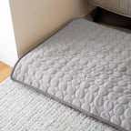 Tapis rafraîchissant gris pour chien posé sur un tapis de salon